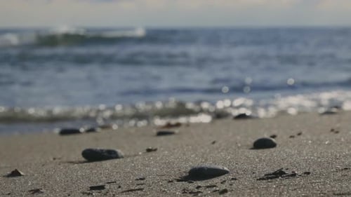 Stones On Sandy Shoreline With Crashing Sea Waves During Sunset. - Close Up, Selective Focus Shot