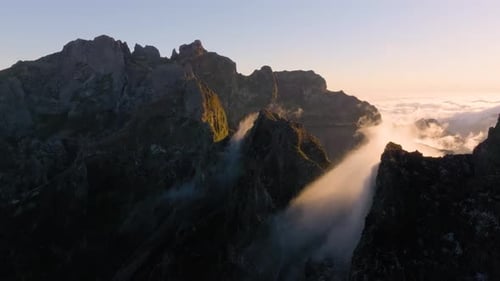 Majestic sunrise over rugged mountain peaks with drifting fog at dawn
