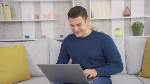 Man Using Laptop Computer and Smiling at Home