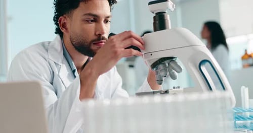 Focused Scientist Using Microscope in Bright Laboratory