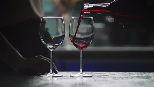 Pouring Red Wine into Glass in Atmospheric Lighting