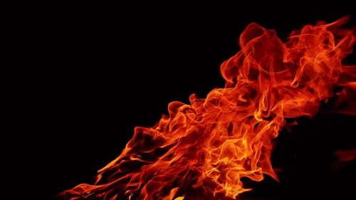 Une longue flamme de feu de joie qui s'étend latéralement sous l'effet du vent. Feu de camp isolé sur fond noir
.