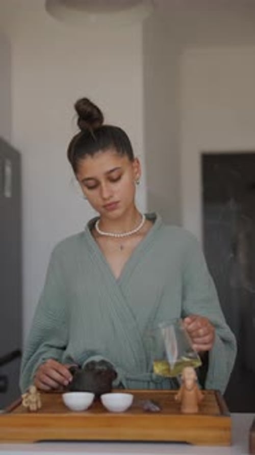 Young Woman Prepares and Pours Tea
