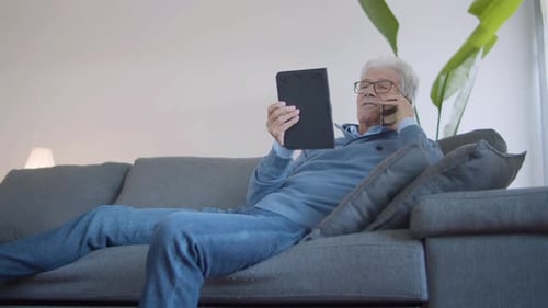 Senior Man Talking on Phone While Holding Tablet