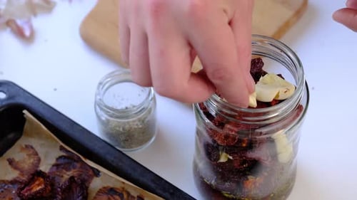 Sun Dried Tomatoes and Garlic Being Placed in Jar