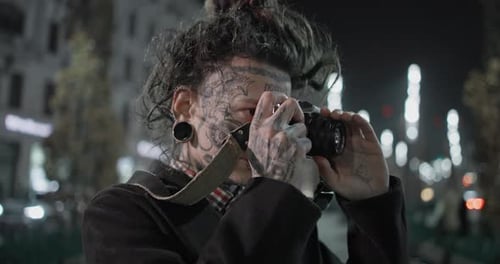 Tattooed Photographer Taking Pictures at Night in City