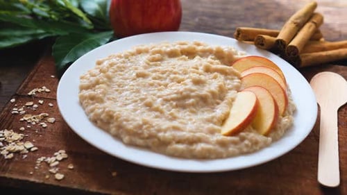 Plate of Oatmeal Porridge with Red Apple Slices and Cinnamon Close Up