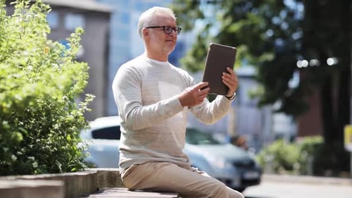 Man sitting uses tablet in city park
