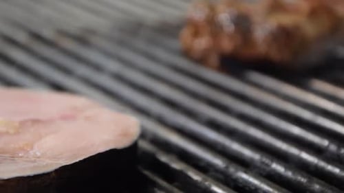 Close Up Grilling a Filet of Swordfish Involved in Smoke.