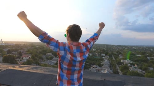 Young Man Celebrates Success on Rooftop at Sunset