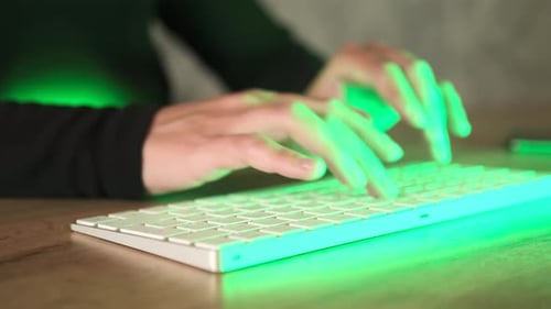Nahaufnahme einer jungen Frau, die schnell eine Nachricht auf der Laptoptastatur vor Neonlichtern eingibt, Seitenansicht.