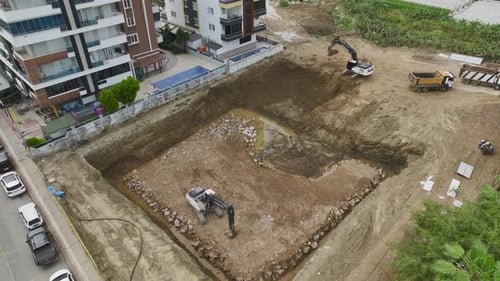 Drone View Construction Workers Unloading Soil Into Foundation