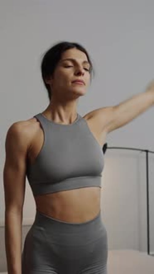 Woman in Sportswear Stretching Arms and Neck Indoors
