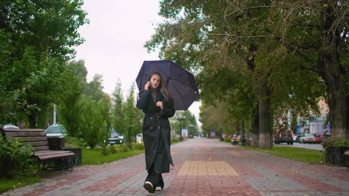 Woman Walks and Talks on Phone in Rainy Park