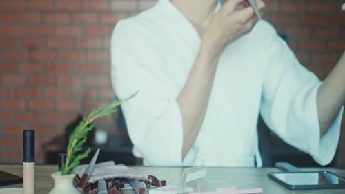 Young Adult Applying Makeup with Brush in Home