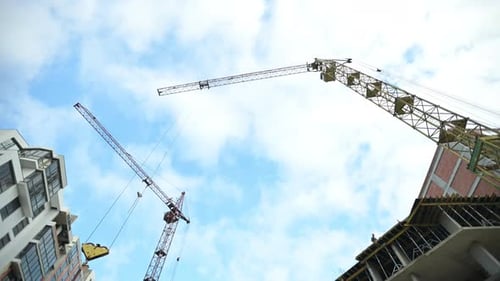 Construction cranes against blue sky. Building process of modern apartment house in city.