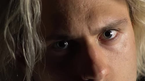 Close up of a blond man look angry at the camera with evil eyes