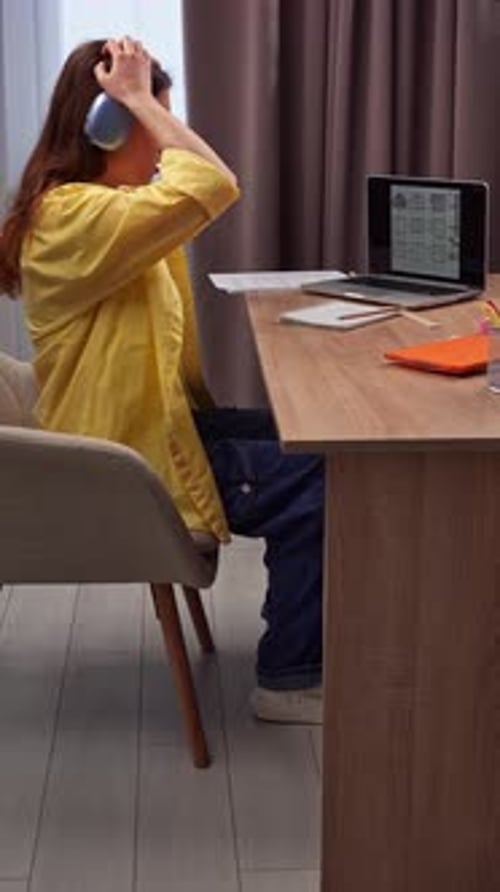 Focused Young Woman Studying with Headphones at Desk
