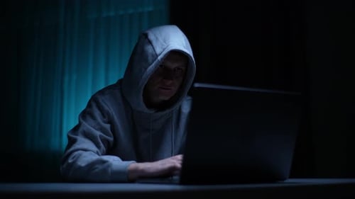 Männlicher Hacker mit Kapuze erhält Zugriff auf Computersystem, das sich mit Laptop in Datenbank-Cyberkriminalität hackt