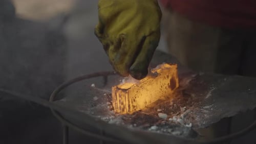 Gloved Hand Applying Powder to Hot Metal Bar