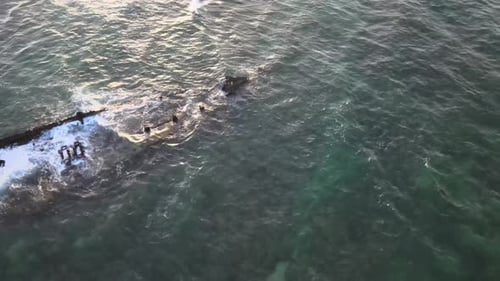 Drone aerial turning and spinning over a shipwreck in the ocean
