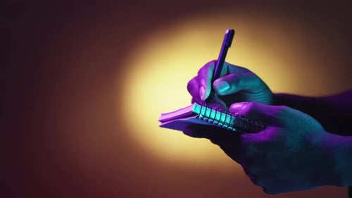 Hands Writing in Notebook with Colorful Lighting