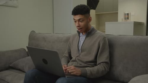 Young Adult Cheering While Working on Laptop Indoors