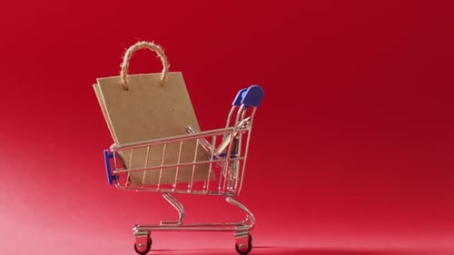 Brown gift bag in shopping trolley on red background