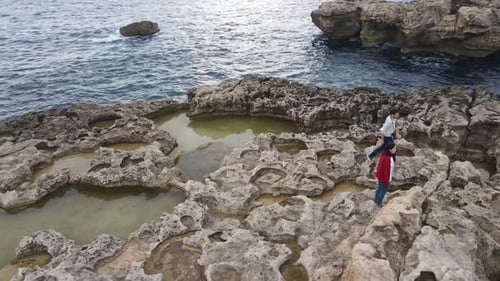 Couple of tourists walking around Fungus Rocks in Dwejra Bay, Gozo Island, Malta. Amazing natural co