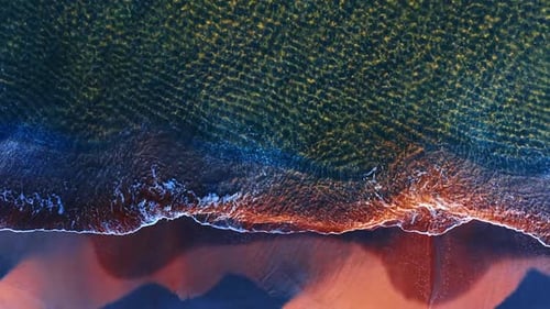 Aerial view shows waves rolling onto sand along the beach.