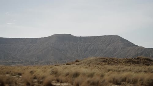 Mountain in the Middle of the Desert on a Day with Sun and Wind Moving the Grass
