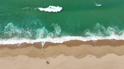 Breathtaking Aerial View of a Pristine Beach and the Waves Gently Rolling on Golden Sand