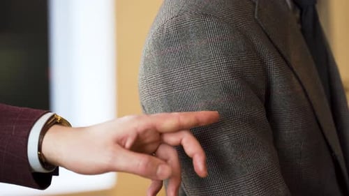 Showing fabric quality of tweed jacket sleeve on customer, close up.