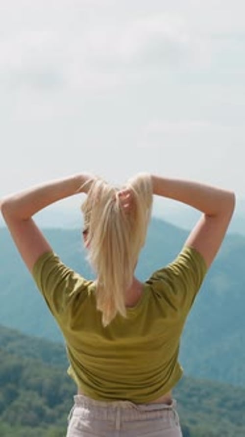 Elegant Woman Lifts Up Hair at Picturesque Mountain Valley