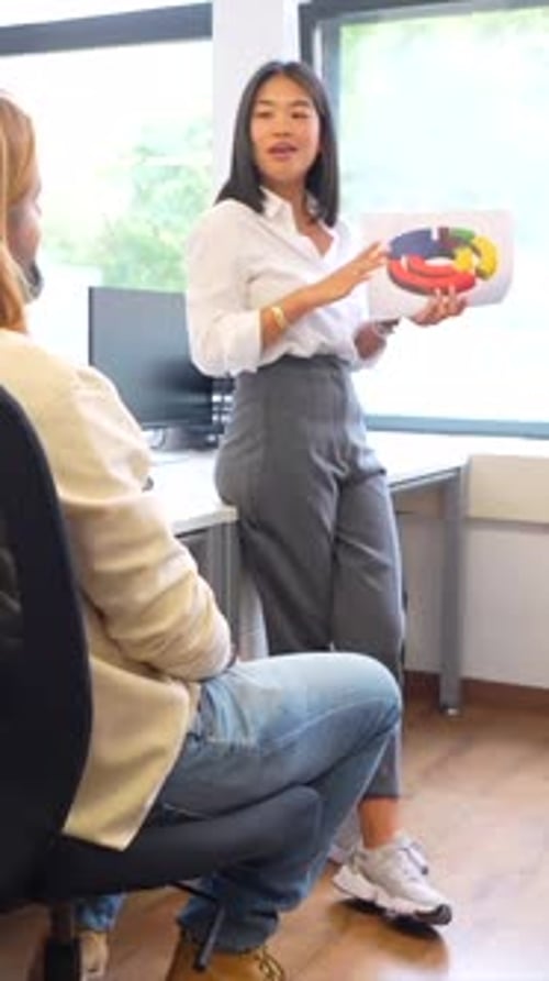 Businesswoman Presents Colorful Chart to Coworkers in Modern Office