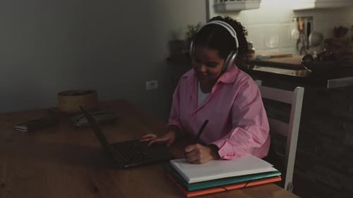 Woman Working on Laptop and Writing in Notebook