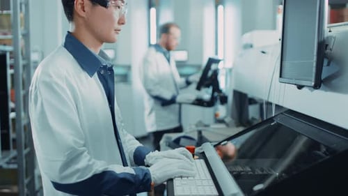 In einer High-Tech-Fabrik verwendet ein asiatischer Ingenieur einen Computer zur Programmierung von Elektronisch Pick-and-Place-Maschinen