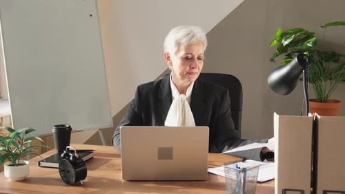 Mature Woman Typing on Computer in Office