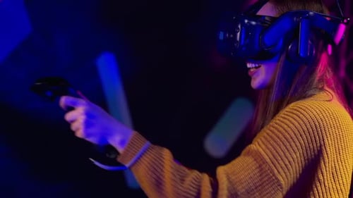 Woman playing VR games in a studio with blue pink neon lights