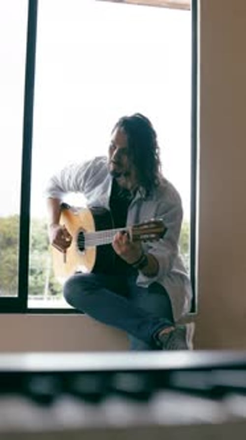 Man Playing Guitar in Window Light, at Home