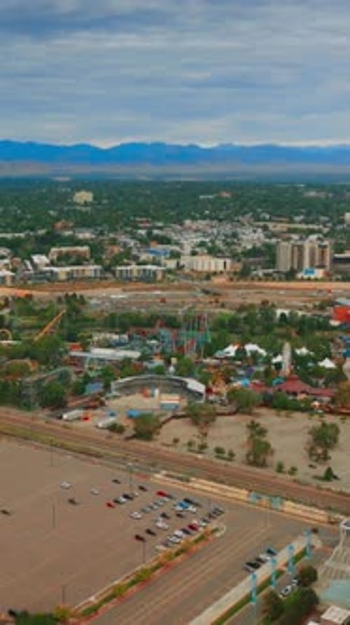 Flying above huge almost empty parking lot with few cars only. View of the big amusement park