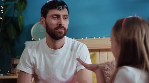 Smiling Father and Daughter Playing Together in Bedroom
