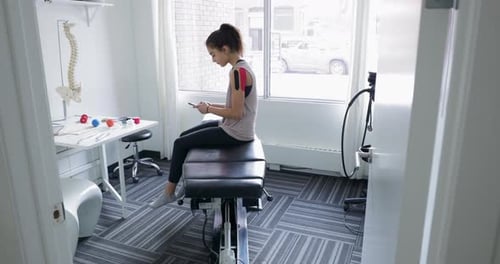 Young Client at Physiotherapy Clinic Using Phone Assistance
