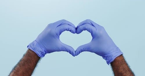 Closeup, hands and gloves with healthcare, heart and thank you on a blue studio background