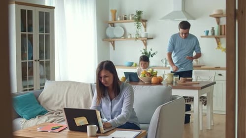 Busy Mom Working Remotely with Laptop Sitting on the Couch Working From Home During a Quarantine