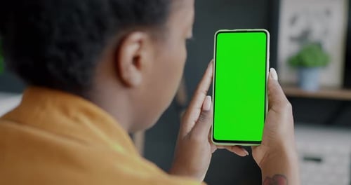 Over the Shoulder Shot of Female Employee Holding Chroma Key Green Screen Smartphone in Office