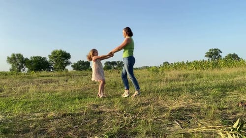 Mother and Daughter Twirling in Grassy Field