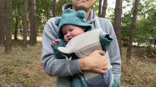 Young Father with His Newborn Baby in a Sling Walking in the Autumn Forest The Concept of a Happy