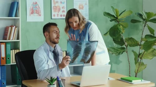 Couple of Private Clinic Workers Analyzing Lungs Xray Scan in the Office Group Portrait Caucasian