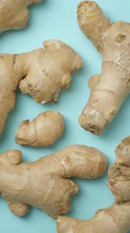 Fresh ginger roots spinning close-up vertical top view